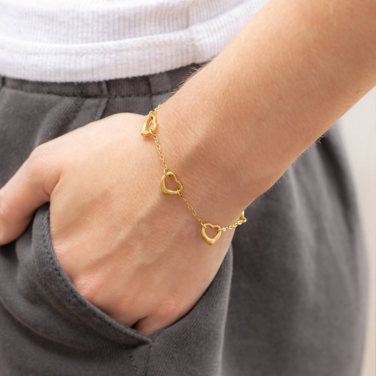 Gold open heart bracelet on wrist with hand in pocket, showcasing minimalist waterproof jewelry perfect for everyday stacking.