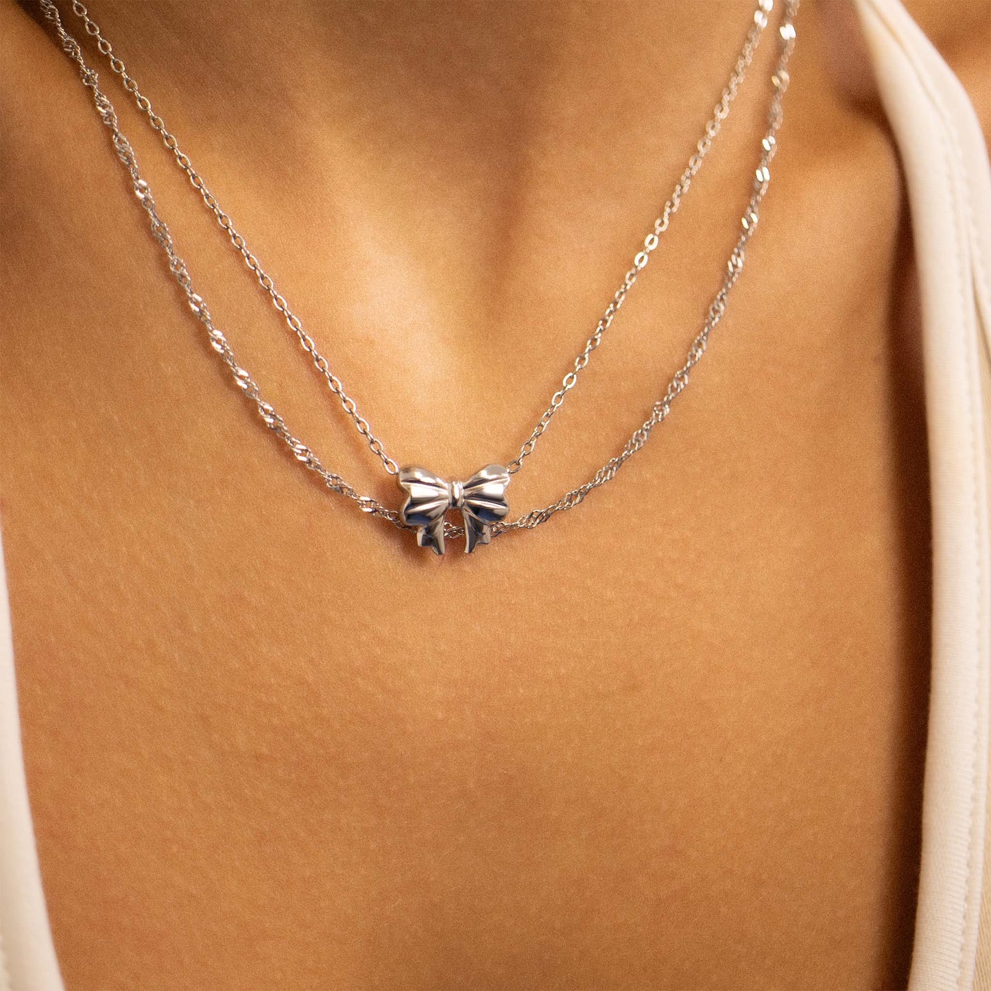 Layered silver bow necklace on model’s neck, waterproof and hypoallergenic from Lauren Riley Jewelry