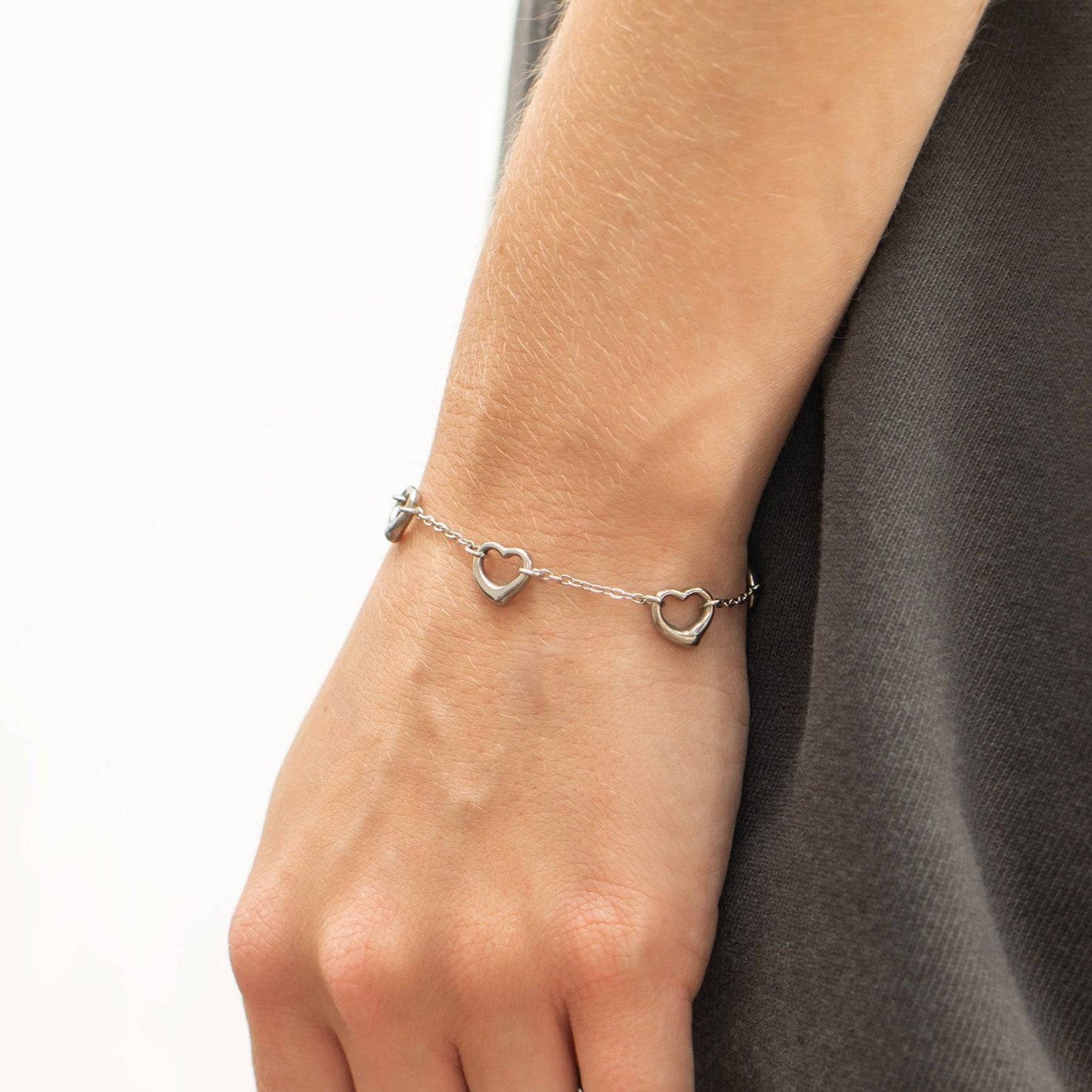 Silver open heart bracelet worn on wrist, featuring dainty waterproof and tarnish-resistant design ideal for stacking with everyday jewelry.