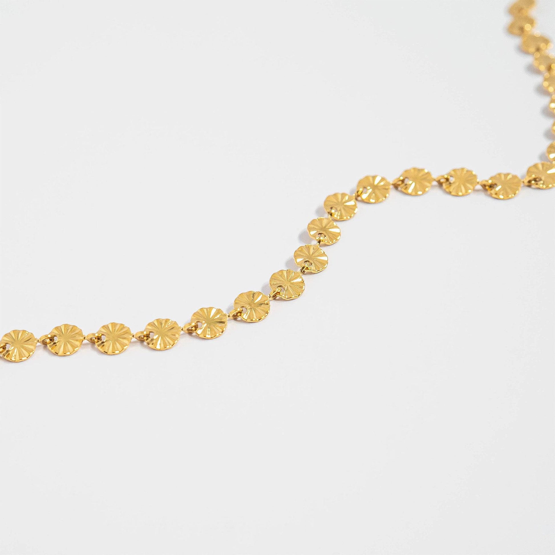 Close-up of gold sunburst disc chain necklace with shimmering waterproof and hypoallergenic finish