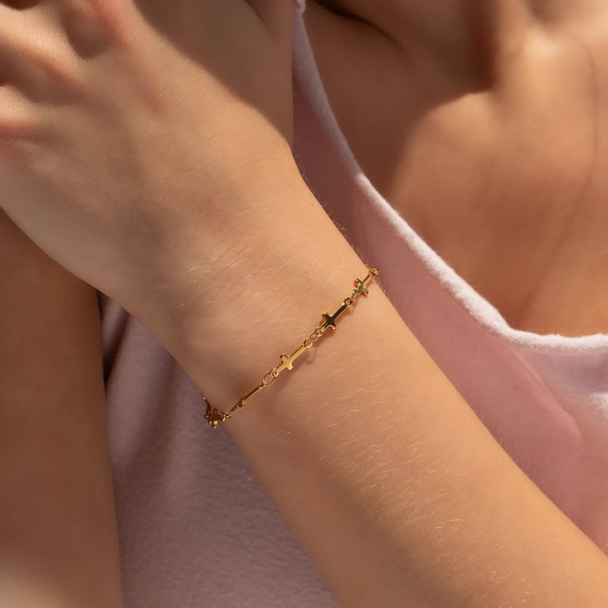 Model wearing dainty gold cross link bracelet. Waterproof, tarnish-free, and hypoallergenic design—perfect for layering or everyday faith-inspired style.
