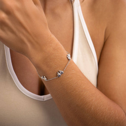 Dainty silver bow bracelet on wrist, crafted from stainless steel with waterproof, hypoallergenic finish — stylish for everyday stacking.