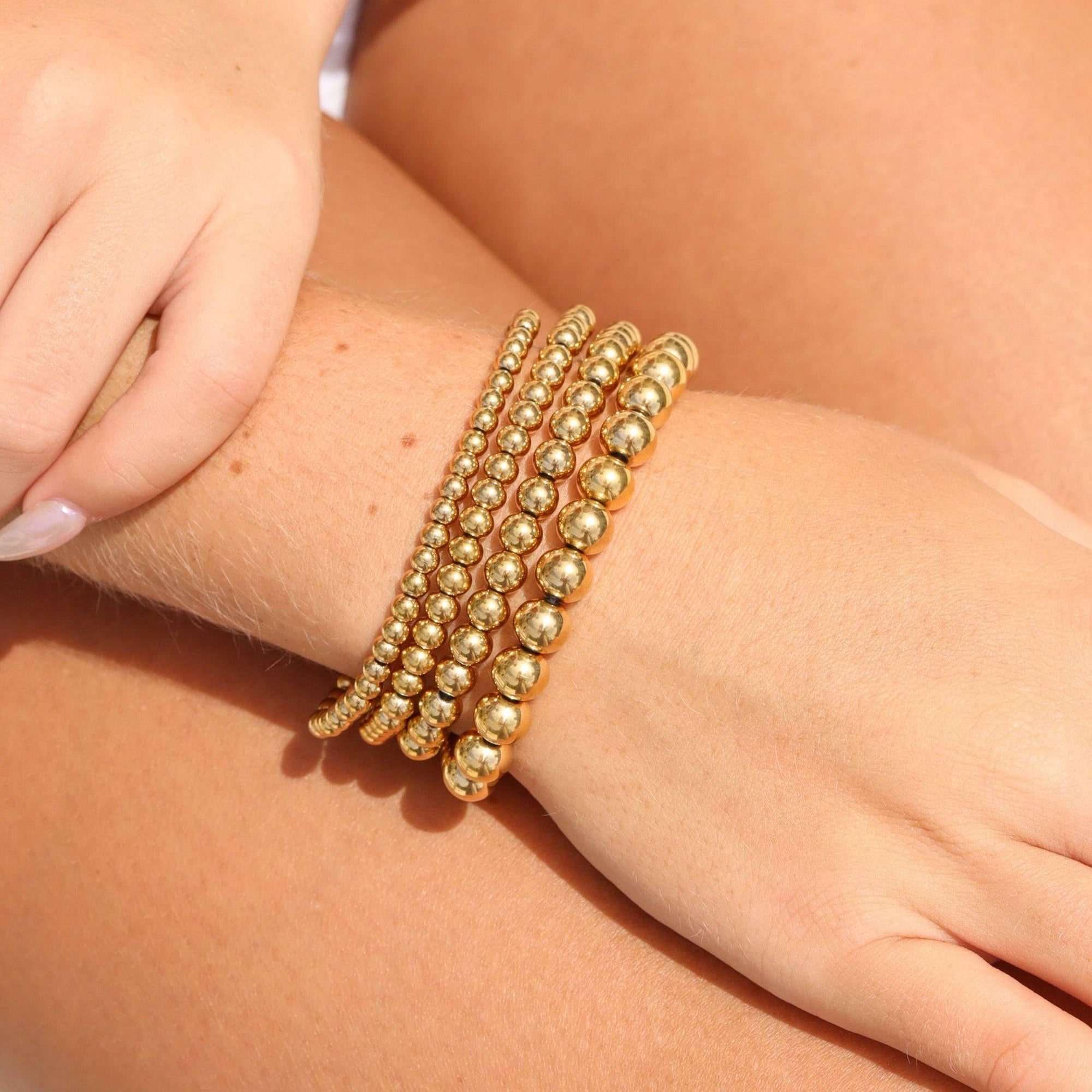 Gold beaded bracelet stack on display stand – waterproof, hypoallergenic, and tarnish-resistant jewelry from Lauren Riley Jewelry