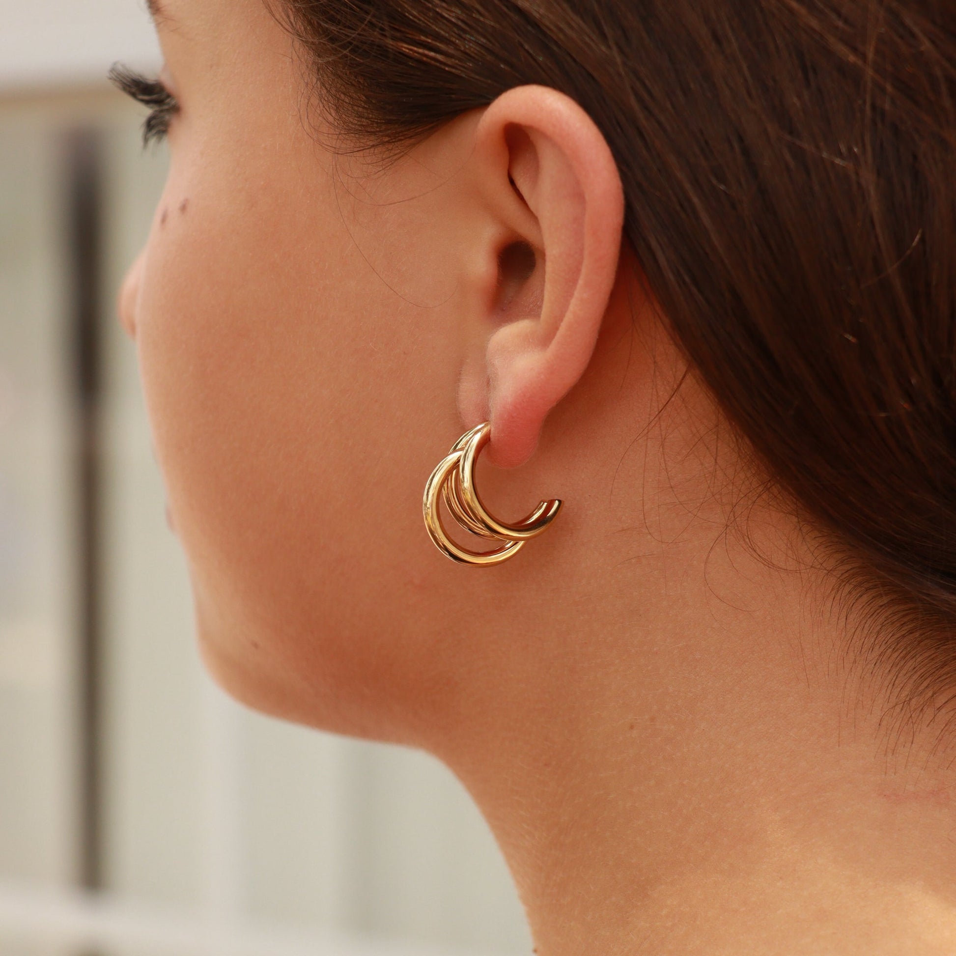 Model wearing gold triple layer hoop earrings – hypoallergenic, waterproof stainless steel jewelry with high-shine PVD finish