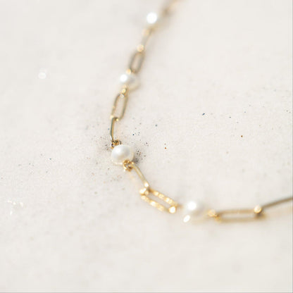 Close-up of gold pearl paperclip chain necklace – hypoallergenic and waterproof jewelry on sand background