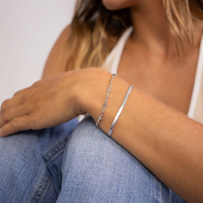 Layered silver cross bracelet styled with bangle. Waterproof, nickel-free, and tarnish-resistant—perfect for everyday wear or gifting.