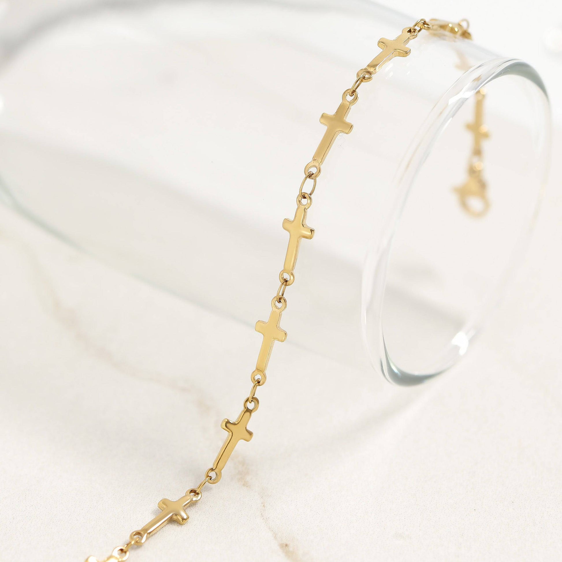 Minimalist gold cross link bracelet displayed on a glass. Elegant waterproof jewelry perfect for everyday wear and stacking. Hypoallergenic and tarnish-free.