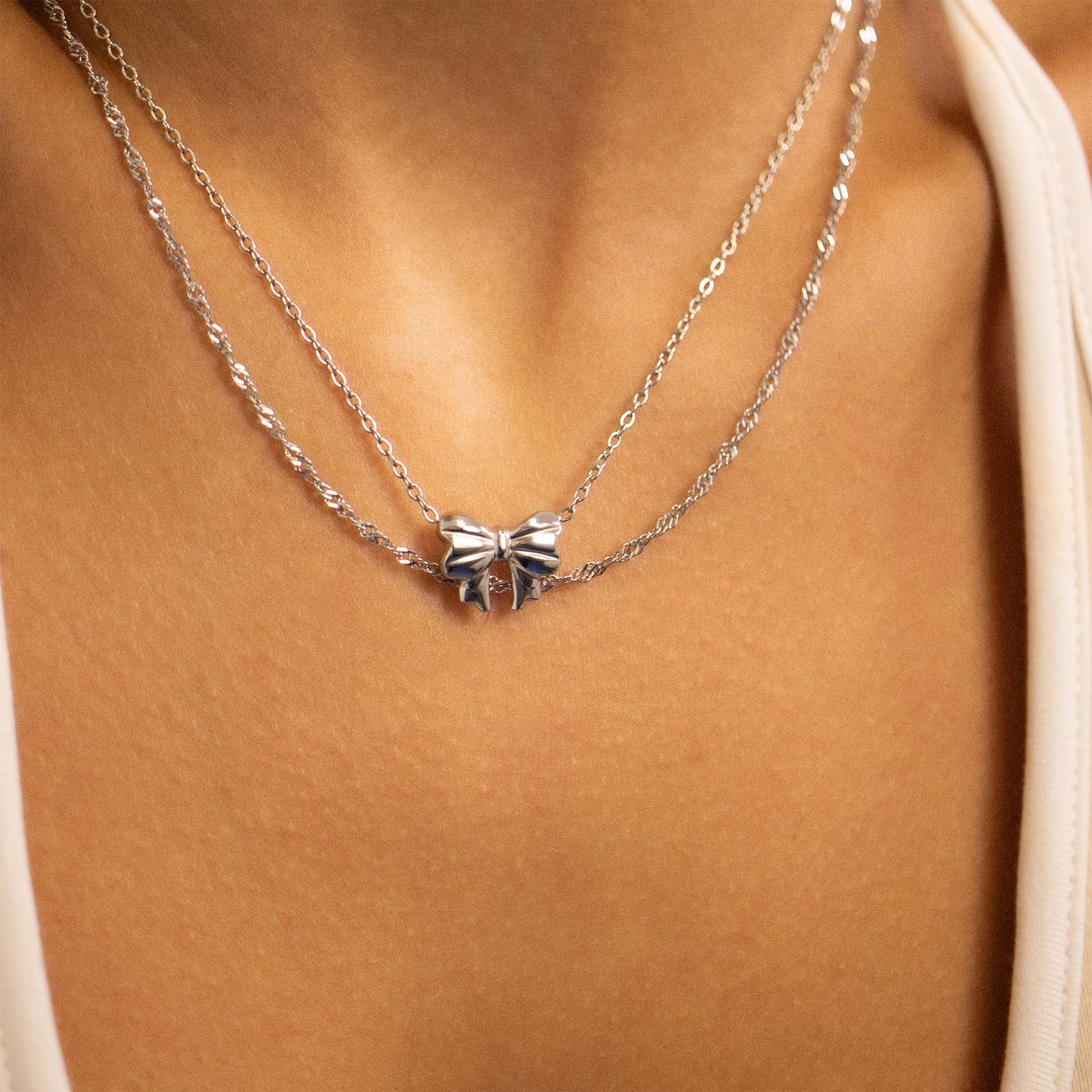 Layered silver bow necklace on model’s neck, waterproof and hypoallergenic from Lauren Riley Jewelry