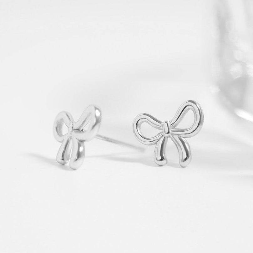 Minimalist silver bow stud earrings displayed on white background, perfect dainty gift for her and ideal for sensitive ears