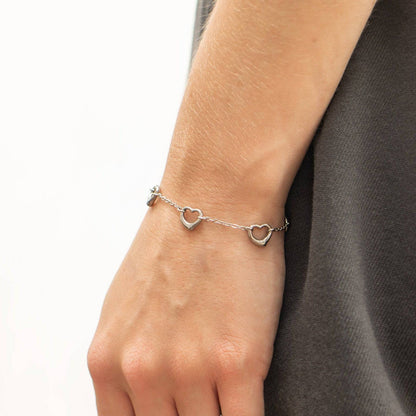 Silver open heart bracelet worn on wrist, featuring dainty waterproof and tarnish-resistant design ideal for stacking with everyday jewelry.