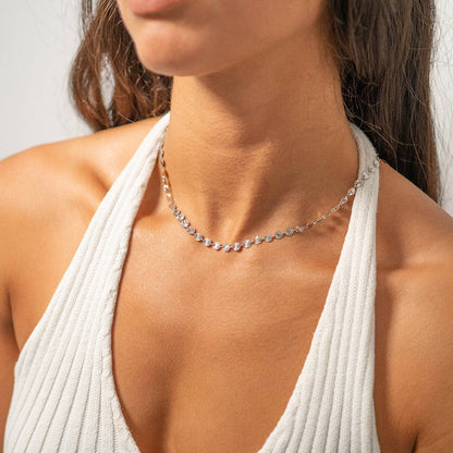 Model wearing silver sunburst disc chain necklace styled for a layered look, waterproof and hypoallergenic jewelry